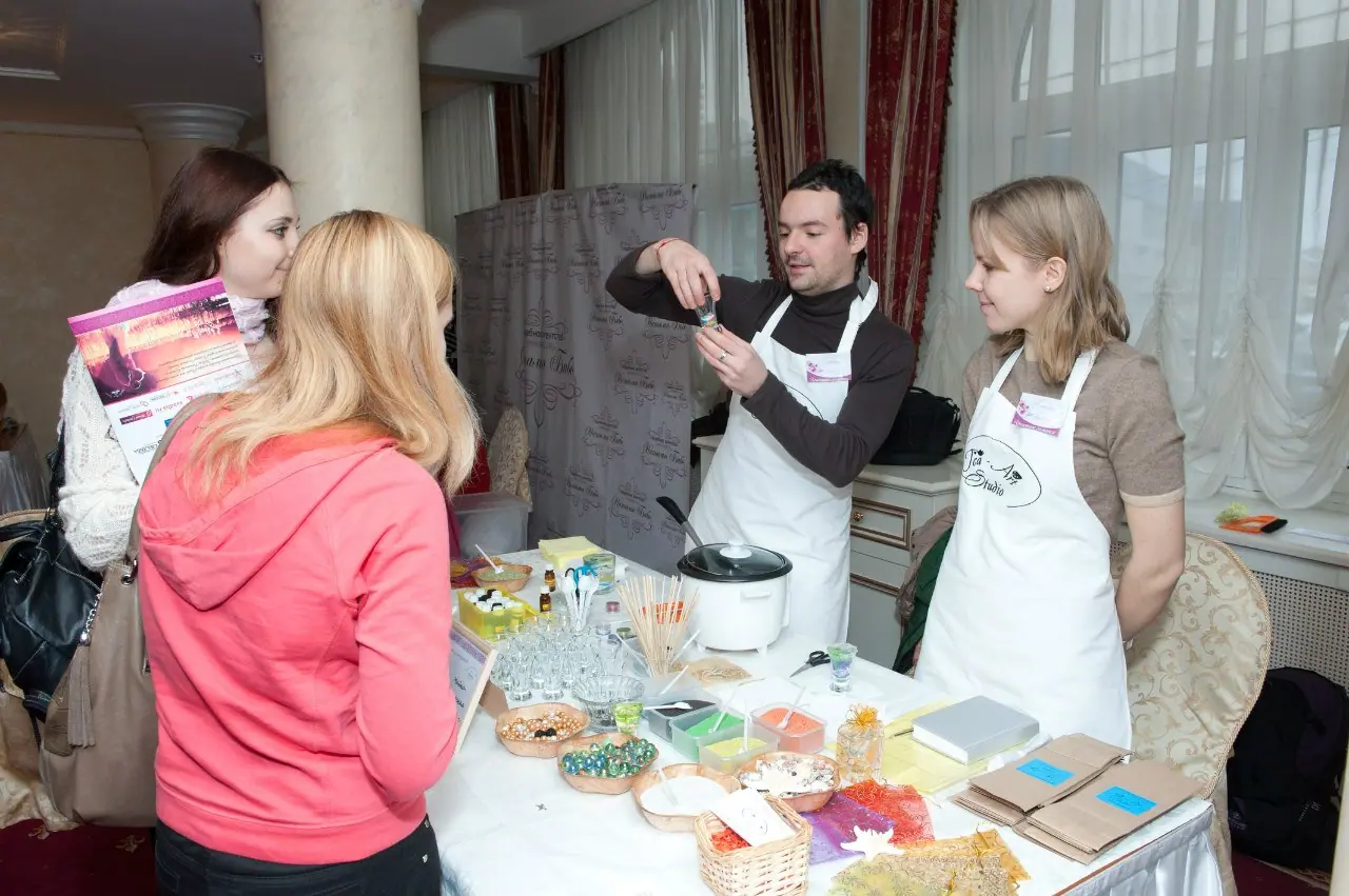 Двое мастеров в фартуках Tea Art Studio за столом с материалами для мастер-класса, перед ними гости